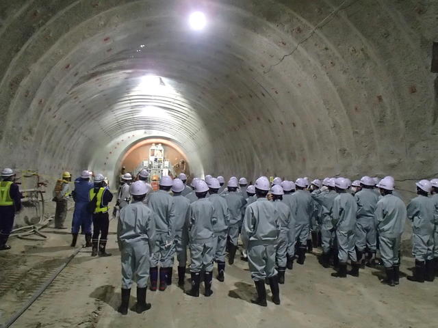 トンネル掘削機械(ドリルジャンボ)による岩盤削孔作業を見学する写真