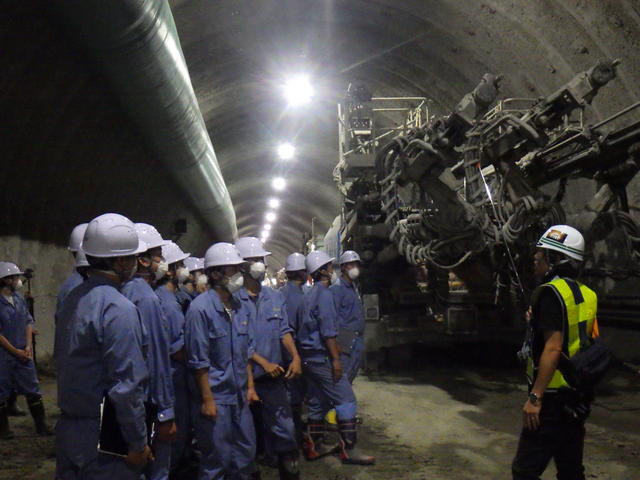 トンネル掘削機械(ドリルジャンボ)を間近で見学する盛岡工業高校の生徒たちの写真