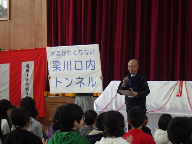 県南広域振興局土木部木村技術主幹兼道路整備課長からトンネル名称発表している写真(奥州市立梁川小学校)